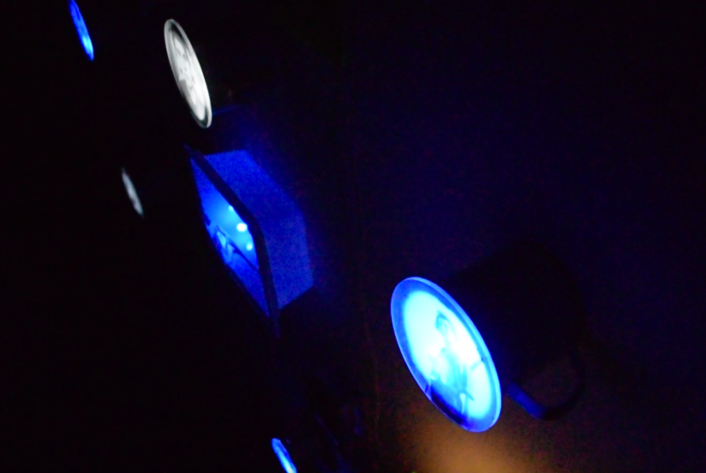 Milcianas_copy_right - BRISA MP Blue circular displays glowing in a dark room, showing portraits as part of a light installation.